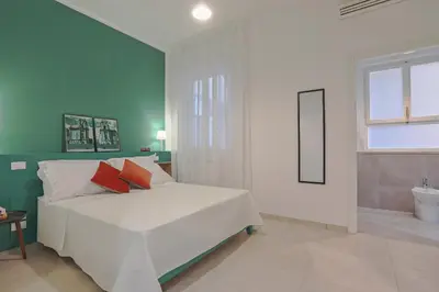 a bedroom with a white bed and a bathroom at Libertà Central Suites in Palermo