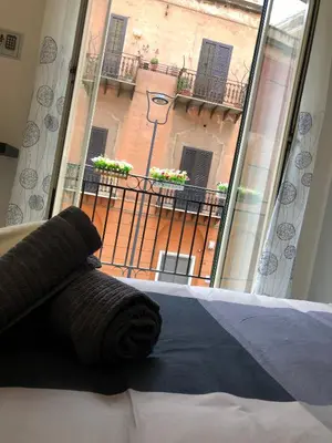 a bedroom with a bed and a window with a balcony at Dal Barce Rooms in Palermo