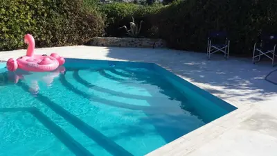 a large blue swimming pool with chairs in a yard at Villa Flore - Penthouse - apartment in villa in Casteldaccia