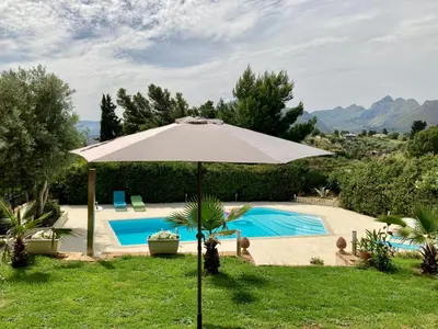 an umbrella in the grass next to a swimming pool at Villa Flore - Penthouse - apartment in villa in Casteldaccia