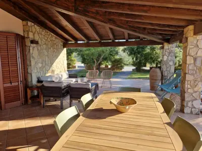a wooden table and chairs on a patio at Villa del Carrubo a due passi dal mare di Cefalù in Collesano