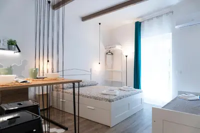 a blue chair sitting next to a bed at Carrettieri54 - apartment historic center Palermo in Palermo