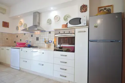 a kitchen with white cabinets and a refrigerator at Villa Mirage in Alcamo