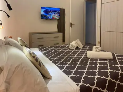 a bedroom with a bed and a tv on the wall at Case Vacanze Mare Nostrum - Villas in front of the Beach with Pool in Campofelice di Roccella