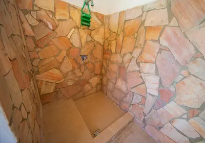a shower in a room with a stone wall at Case Vacanze Mare Nostrum - Villas in front of the Beach with Pool in Campofelice di Roccella