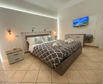 a bedroom with a large bed and a television at Case Vacanze Mare Nostrum - Villas in front of the Beach with Pool in Campofelice di Roccella