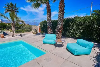 two blue chairs next to a swimming pool with palm trees at Villa Ciuridda in Alcamo