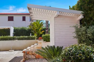 a wooden garage with a white pergola in a yard at Villa Ciuridda in Alcamo