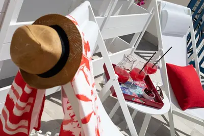 a straw hat sitting next to a table with a drink at Coral Holiday San Vito Lo Capo in San Vito lo Capo