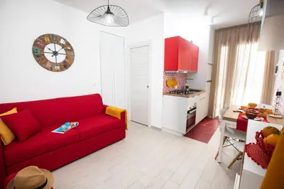 a living room with a red couch and a kitchen at Coral Holiday San Vito Lo Capo in San Vito lo Capo