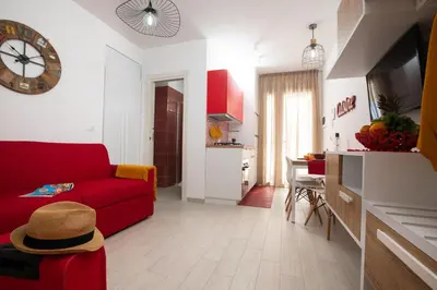 a living room with a red couch and a clock at Coral Holiday San Vito Lo Capo in San Vito lo Capo