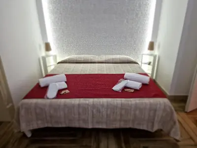 a bed with a red blanket and white towels on it at Calypso Il Binario Elegance in Palermo