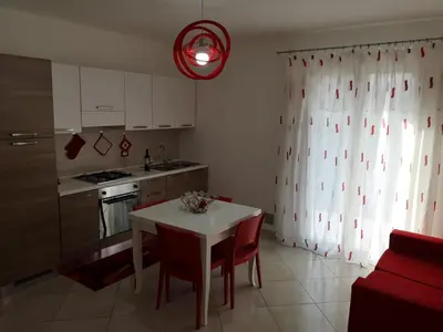a kitchen with a white table and red chairs at Casetta 
