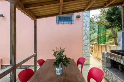 a wooden table with red chairs and a vase with flowers at La Casa nell'Oliveto a San Martino in Monreale
