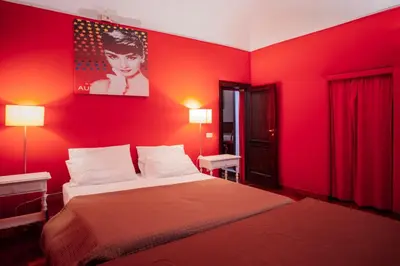 a bedroom with a red wall with a bed at Cinematocasa Suite in Palermo