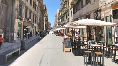 an empty street with tables and chairs and umbrellas at Cinematocasa Suite in Palermo