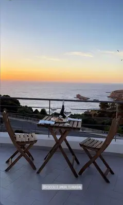 a table and two chairs on a balcony with the ocean at Cocciu d’amuri in Terrasini