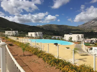 a swimming pool in a town with mountains in the background at Villa Edori - Giardino degli Allori in Castellammare del Golfo