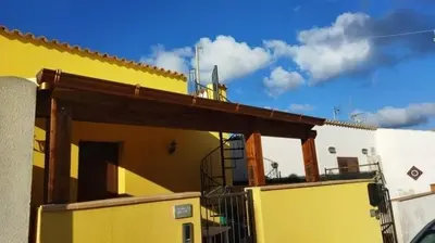 a yellow house with a wooden roof at Appartamento a San Vito lo capo in San Vito lo Capo