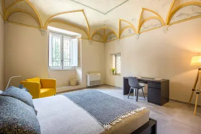 a bedroom with a bed and a desk and a chair at Casa dell'Architetto alla Cattedrale by Wonderful Italy in Palermo