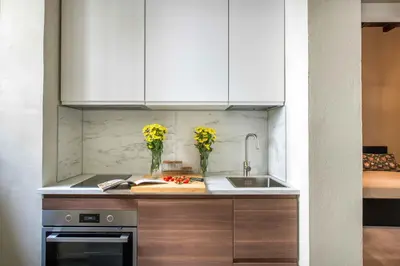 a kitchen with white cabinets and vases of yellow flowers at Casa dell'Architetto alla Cattedrale by Wonderful Italy in Palermo