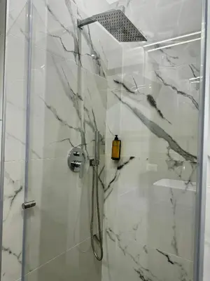 a bathroom with a shower with marble walls at Palermo Inn in Palermo