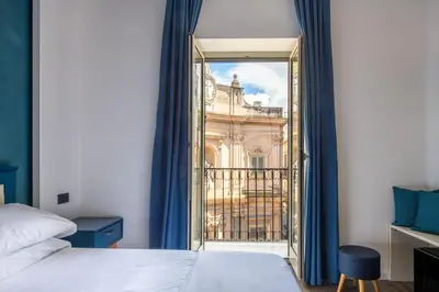 a bedroom with a bed and a view of a building at Villena Plaza by Wonderful Italy in Palermo