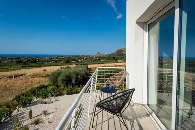 a balcony with two chairs and a view of the desert at Giardino degli Allori - Villa Flores in Castellammare del Golfo