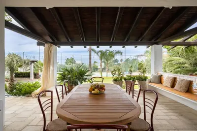 a wooden table and chairs on a patio at Villa a 300 Mt. dal Mare (Magaggiari) con campo da tennis in Cinisi