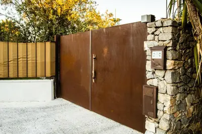 a wooden gate with a stone wall next to a fence at Villa Bienvenue in Carini