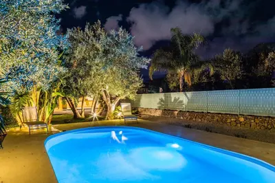 a swimming pool in a backyard at night at Villa Bienvenue in Carini