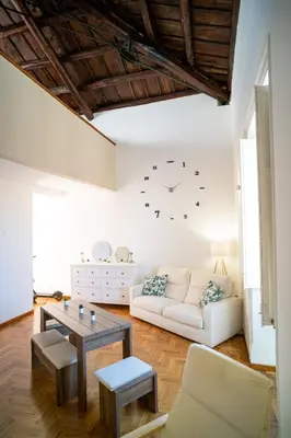 a living room with a white couch and a clock on the wall at Suite Cathedral Palermo in Palermo