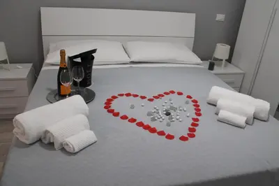 a bed with a heart on it with towels and a bottle of wine at Rigoletto Holiday Home,Centrocittà Palermo in Palermo
