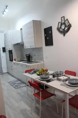 a kitchen with a table and red chairs in a kitchen at Rigoletto Holiday Home,Centrocittà Palermo in Palermo