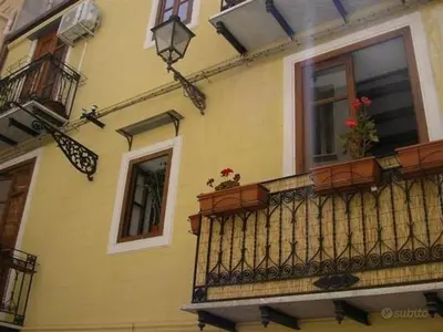 a yellow building with a balcony with flowers on it at Home Casa Professa 1 in Palermo