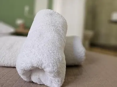 a roll of white towel sitting on a bed at Teatro Del Sole Apartment in Palermo
