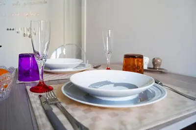 a table with a plate and two wine glasses on it at Le case di Ninni - Monfenera in Palermo