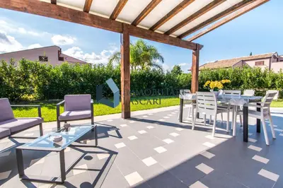 a patio with a table and chairs and a pergola at Villa Luana, a pochi passi dal mare in Lascari