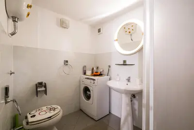a white bathroom with a washing machine and a sink at Surplus Charming Apartment in Palermo
