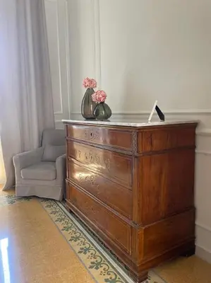 a dresser with flowers on top of it next to a chair at BARRIQUE Guest House in Palermo
