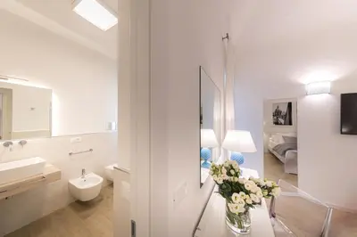 a bathroom with a sink and a vase of flowers on a table at La Home42 Suite in Palermo