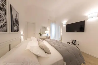 a white bedroom with a bed and a tv on the wall at La Home42 Suite in Palermo
