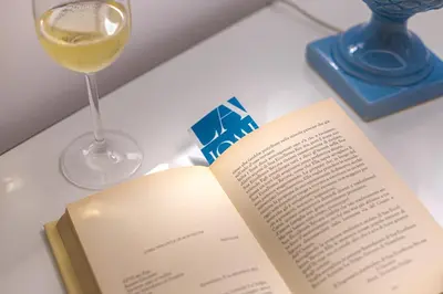 a book and a glass of wine on a table at La Home42 Suite in Palermo