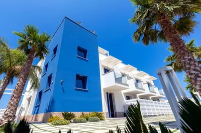a blue building with palm trees in front of it at Sundeck Hotel in San Vito lo Capo