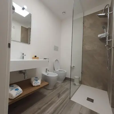 a bathroom with a toilet and a sink and a shower at Sundeck Hotel in San Vito lo Capo