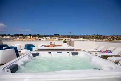 a man laying in a hot tub on a roof at Sundeck Hotel in San Vito lo Capo