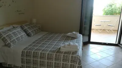 a bedroom with a bed and a balcony with a table at Dimora Di Campagna in Portella di Mare