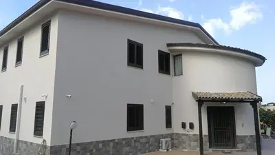 a white building with black shutters on it at Dimora Di Campagna in Portella di Mare