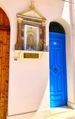 a blue door in a white wall with a shrine at Casa Colore Attic in Castellammare del Golfo