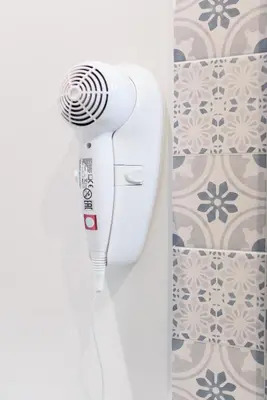 a white hair dryer in a bathroom next to a wall at GUEST HOUSE PIANA DEGLI ALBANESI in Piana degli Albanesi